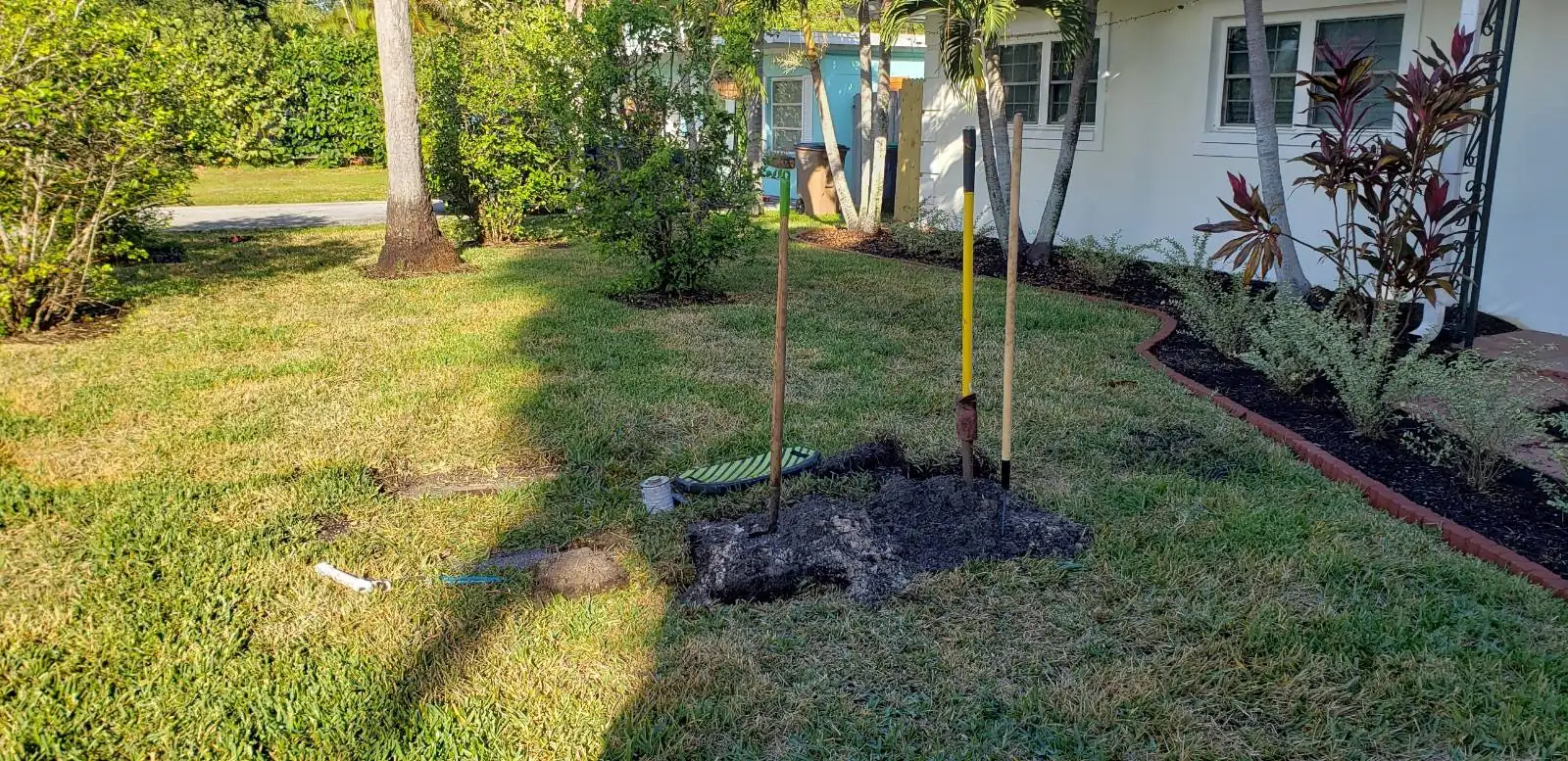 Front yard with new irrigation work underway beside a home