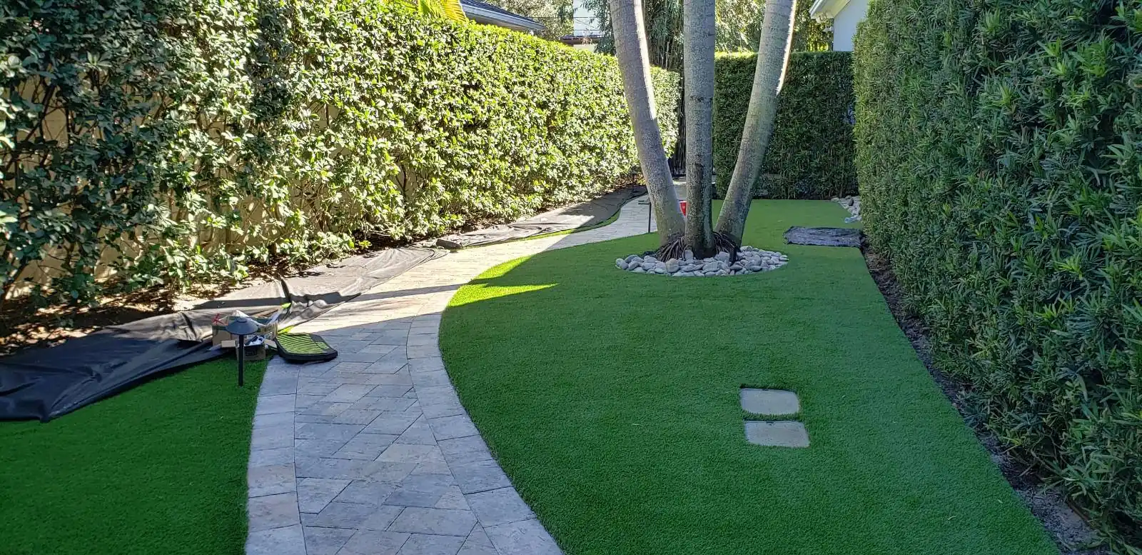 Green lawn and paver walkway between hedges after irrigation work