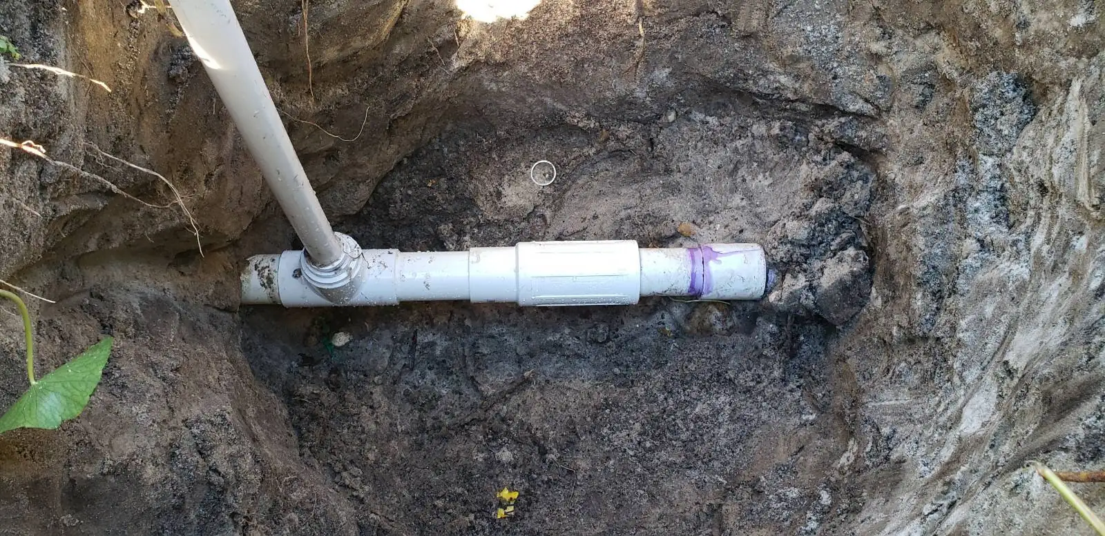 Repaired sprinkler line with new PVC couplings in an open trench